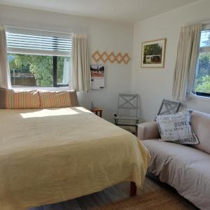 Un dormitorio con una cama y un sofá y una ventana. en Vintage Christie, en Havelock North