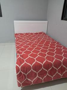 a bed with a red and white comforter at Apartamento na cidade do kilamba Luanda in Camama