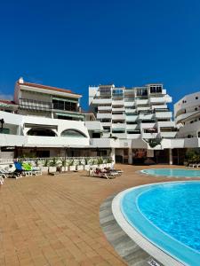 a large building with a swimming pool next to a resort at Fañabe Stunning Beachfront Penthouse Parque Royal Adeje Tenerife in Adeje