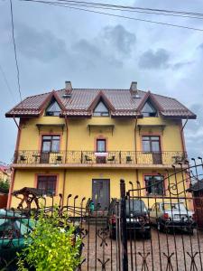 a yellow house with cars parked in front of it at Вілла Львів in Skhidnitsa