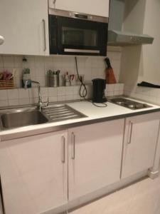 Una cocina con gabinetes blancos, un fregadero y un microondas. en Euclide apartment, en Roma