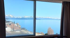 ein großes Fenster mit Blick auf einen Wasserkörper in der Unterkunft El encanto del lago in San Carlos de Bariloche