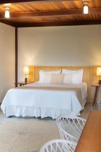 1 dormitorio con 1 cama blanca grande y 2 sillas en Casas Gengibre, en Alto Paraíso de Goiás