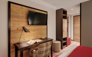 ein Hotelzimmer mit einem Schreibtisch und einem TV an der Wand in der Unterkunft Hotel Traumschmiede in Unterneukirchen