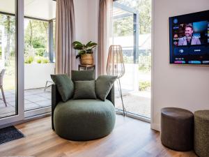 a living room with a chair and a tv at Family Home Near Hoge Veluwe Park in Voorthuizen