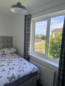 a bedroom with a bed and a large window at Sleeps 7 in Pembrokeshire