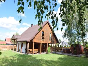 a wooden house with a porch and a fence at Holiday Home by Lake Zarnowieckie with Sauna in Nadole