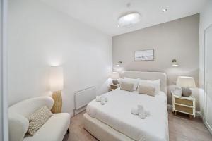 a white bedroom with a white bed and a chair at Portsalon Cottage in Portsalon