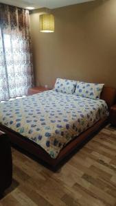 a bedroom with a bed with a blue comforter at Appartement Alkheir in Agadir