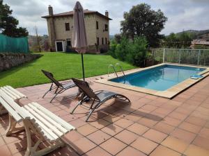 a patio with two chairs and an umbrella next to a pool at Mirador de San Marcos in Soria