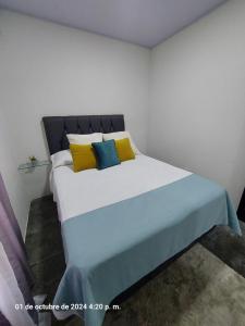 a bedroom with a large bed with yellow and blue pillows at DEPARTAMENTOs HABY 1 in Paquera