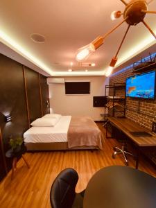 a bedroom with a bed and a desk and a television at Sensitive in Santo Antônio