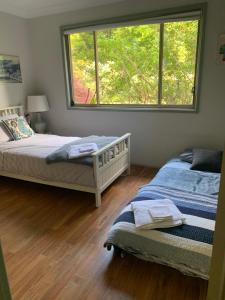 Grandmas Cottage Fairmont في Woodhill: غرفة نوم بها سريرين ونافذة كبيرة