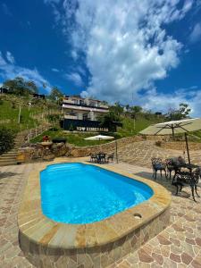a blue swimming pool in a patio with tables and chairs at Esmeralda PLUS in San Gil