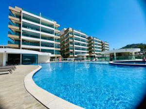 a large swimming pool in front of a building at Apartamento dos Sonhos na Praia dos Anjos in Arraial do Cabo