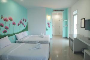 two beds in a room with flowers on the wall at Like Residence in Suratthani