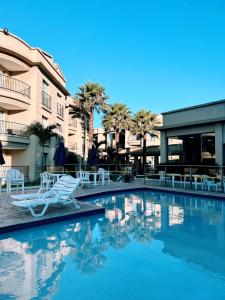 una piscina con sedie bianche e un edificio di Flat Aldeia das Águas a Volta Redonda