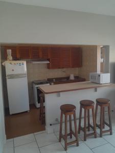 a kitchen with a counter and three bar stools at Apartamento Praia Grande in Ubatuba