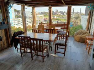 a dining room with a table and chairs and windows at Pichilemuhostel SurfersView in Pichilemu