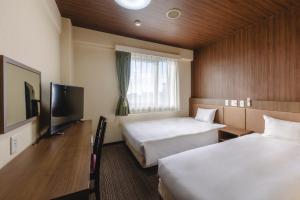 a hotel room with two beds and a flat screen tv at Hotel Wing International Sagamihara in Sagamihara +63 photos