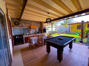 a pool table in the middle of a room with a kitchen at Recantos Pinheiros - Casa inteira, até 15 hóspedes - Piscina privativa, sinuca, ar condicionado e TVs nos 4 quartos - Condomínio Orla 500, lado praia - Unamar, Cabo Frio-RJ in Tamoios