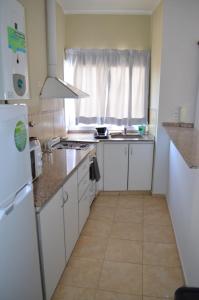 a small kitchen with white cabinets and a window at Complejo Fatima in Villa Dolores