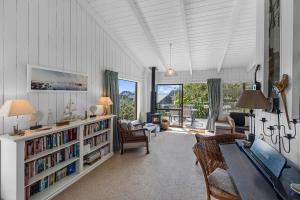 a living room with a table and a book shelf at Seaview Family Haven - Pauanui Holiday Home in Pauanui