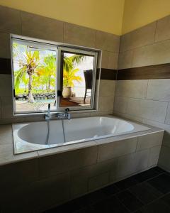 a bath tub in a bathroom with a window at La maison du Bonheur Raiatea in Tevaitoa