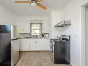 a kitchen with white cabinets and a black refrigerator at Solvang Bungalow A in Solvang