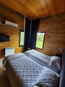 a bedroom with two beds in a room with wooden walls at Casa Cortés Golf - Boutique in Sierra de la Ventana +26 photos