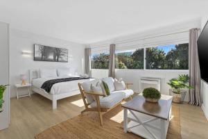 a white bedroom with a bed and a couch at Stay Mission Bay in Auckland