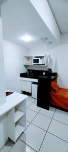 Dieses weiße Zimmer verfügt über ein Bett und eine Mikrowelle. in der Unterkunft Flat Village - Aldeia das águas in Sapucaia