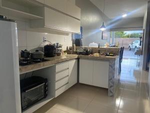 a kitchen with white cabinets and a stove top oven at DUNAS RESIDENCE CASA 13 OU CASA 16 Santo Amaro - Lençóis Maranhenses in Santo Amaro