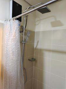 a shower with a white shower curtain in a bathroom at City Serenity Escape in Manila