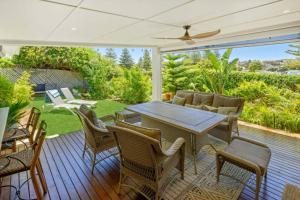 a patio with a table and chairs on a deck at Luxury Spa Beachfront Moana in Moana