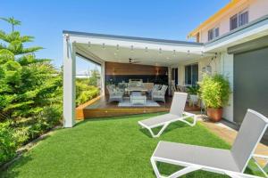 a patio with white chairs and a table on a lawn at Luxury Spa Beachfront Moana in Moana