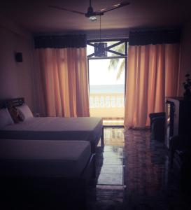 a bedroom with two beds and a large window at Mirissa Seastar in Mirissa