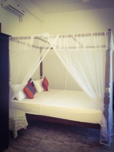 łóżko z białym baldachimem i poduszkami w obiekcie Mirissa Seastar w mieście Mirissa