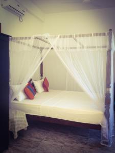 a bed with a white canopy with pillows on it at Mirissa Seastar in Mirissa