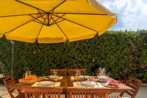 einem Holztisch mit einem großen gelben Regenschirm in der Unterkunft Casa da Graça by An Island Apart in Porto Santo