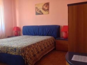 um quarto com uma cama azul e 2 candeeiros em Orange Holiday Home em Torvaianica