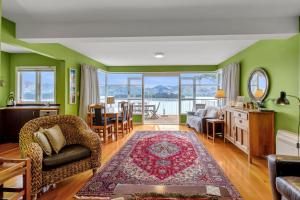 a living room with green walls and a table and chairs at Bayview Beauty - Charteris Bay Holiday Home in Diamond Harbour