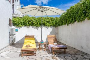 a patio with two chairs and an umbrella at Holiday house with a parking space Milna, Brac - 20140 in Milna +12 photos