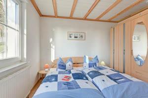 a bedroom with a large bed with blue pillows at Ferienhaus Ostseeblick in Göhren