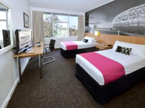 a hotel room with two beds and a desk at Mercure North Melbourne in Melbourne