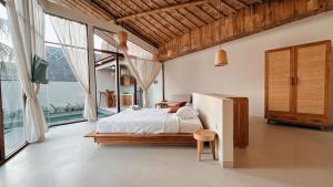 a bedroom with a bed in a room with large windows at Capila Villa Bali in Canggu +17 photos