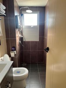 Un baño con inodoro y ventana. en amliza homestay, en Cyberjaya