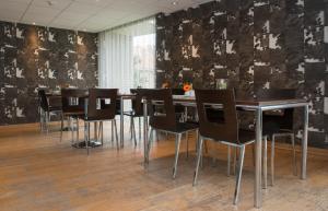 a dining room with black chairs and a table at Hotel Maxim in De Panne