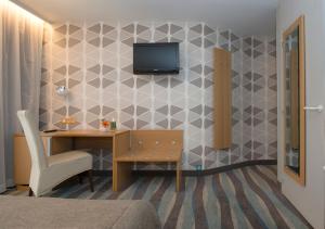 een kamer met een bureau en een tv aan de muur bij Hotel Maxim in De Panne