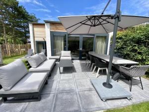 a patio with a table and an umbrella at Holiday Home Nieuwvliet near Beach & Dunes in Nieuwvliet-Bad